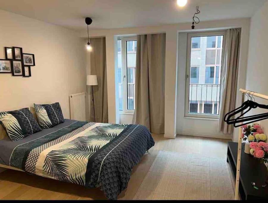 ein Schlafzimmer mit einem Bett und zwei großen Fenstern in der Unterkunft beau studio (parlement européen) in Brüssel