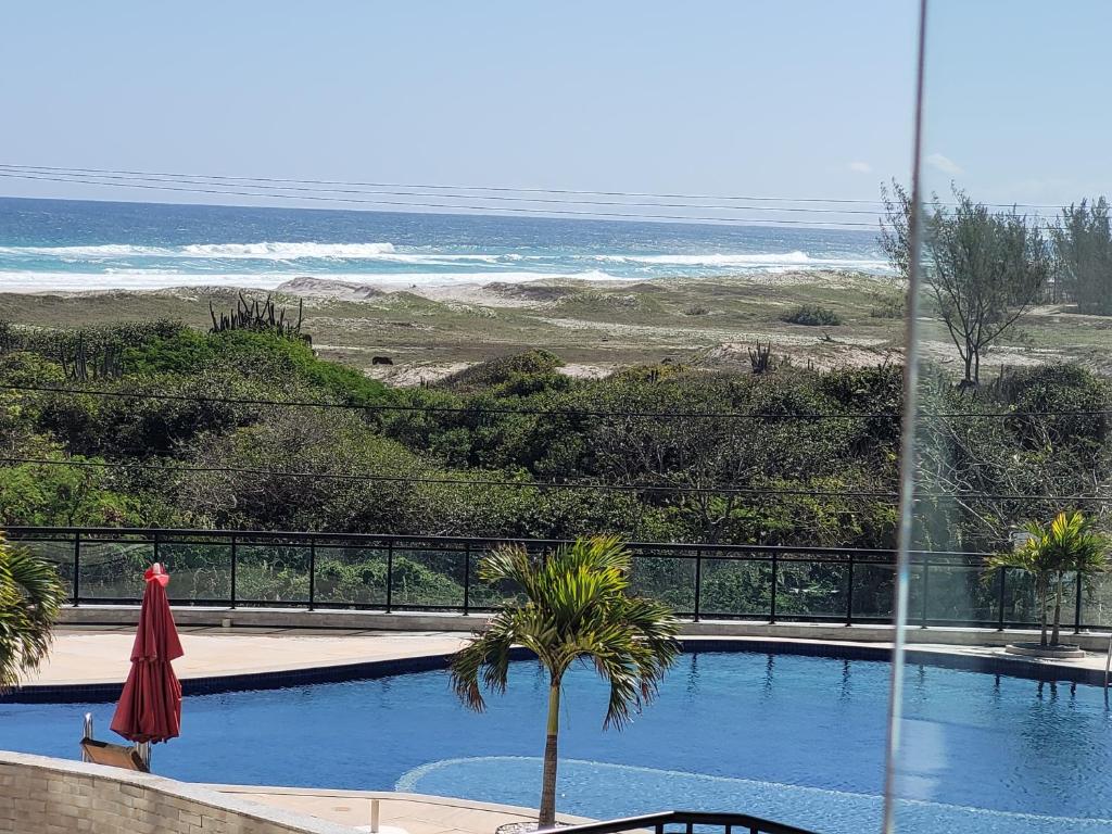 a swimming pool with a view of the ocean at Apto Le Bon Vivant Vista Mar in Arraial do Cabo