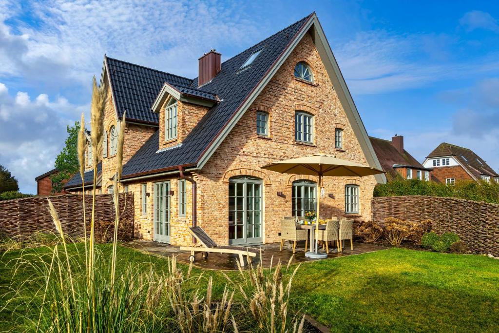 une grande maison en briques avec un toit noir dans l'établissement Haus Westerländer Perle, à Westerland