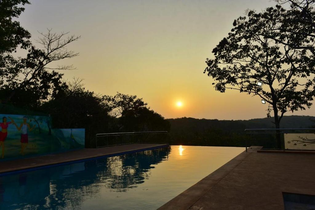 una piscina con puesta de sol en el fondo en santanas wooden cottages en Bogmalo