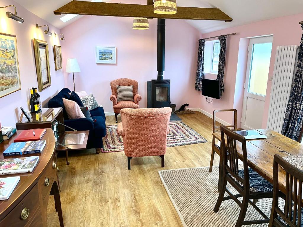 a living room with a fireplace and a table and chairs at Fletchers Cottage in Honiton