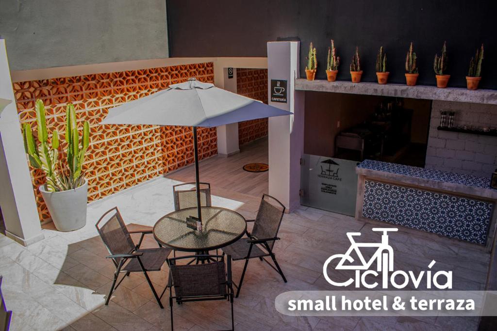 une terrasse avec une table, des chaises et un parasol dans l'établissement Hotel Ciclovía & Terraza, à Zitácuaro