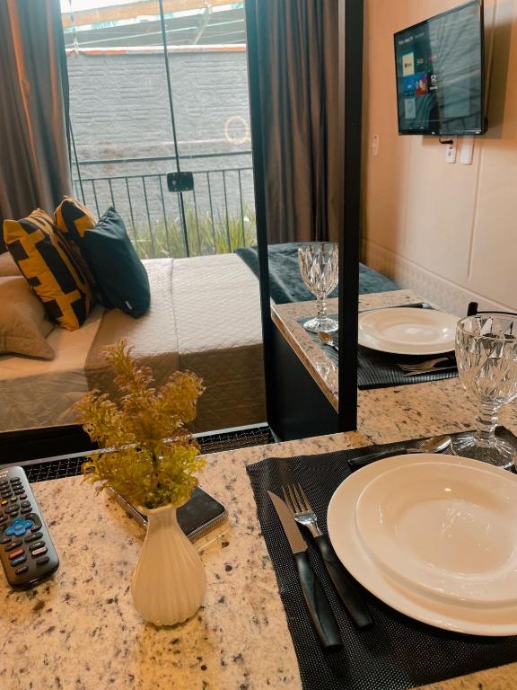 um quarto de hotel com uma mesa com pratos e um quarto com uma cama em LOFT BC em Balneário Camboriú