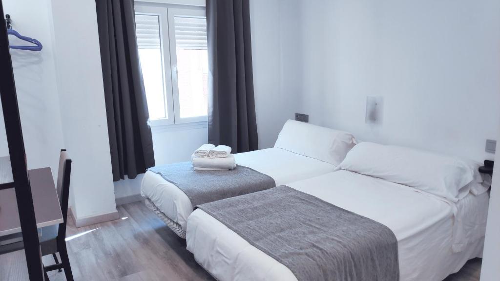 a bedroom with a white bed and a window at Hostal Doña Isabel in Majadahonda