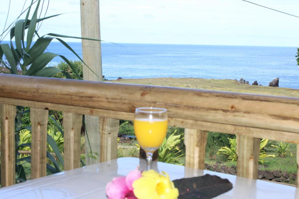 un vaso de zumo de naranja sentado en una mesa en un balcón en Chez Jérôme en Hanga Roa