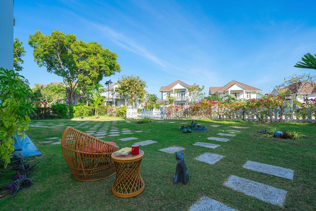 podwórze z dwoma krzesłami i kotem na trawie w obiekcie Casa Villa - Floral Park- Sealinks City Resort w mieście Phan Thiet