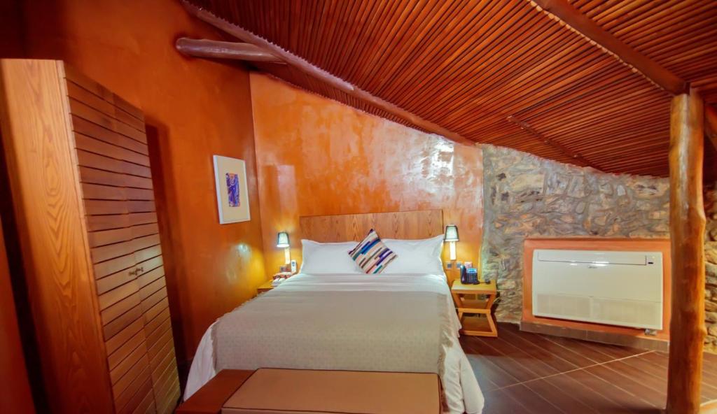 Trois Ore Residences & Green Earth Bistro في إيبادان: غرفة نوم بسرير وتلفزيون