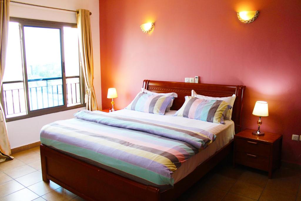 a bedroom with a bed with red walls and two lamps at Residence Le Carat Silverline in Douala