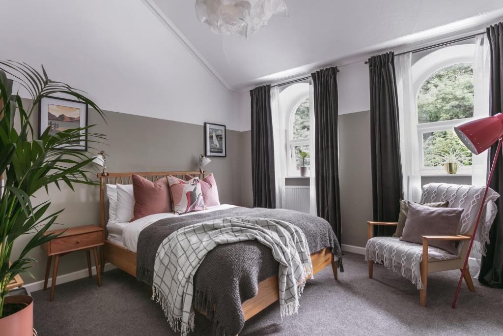 a bedroom with a bed with pink pillows and a chair at 14 Church Street- close to Windermere Train Station in Windermere