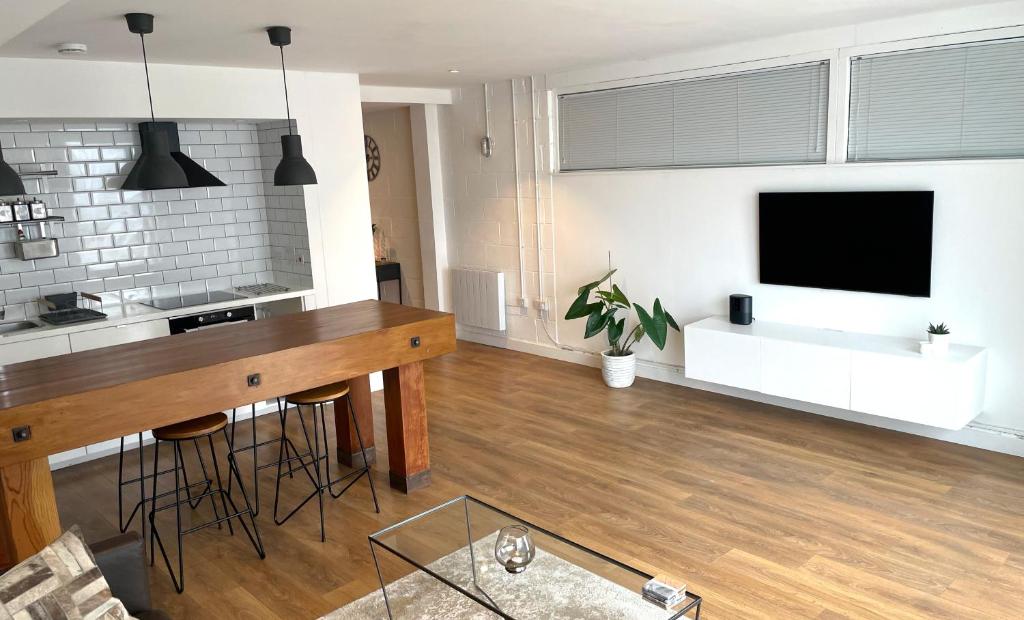 a living room with a table and a flat screen tv at Spacious Industrial style Apartment in London