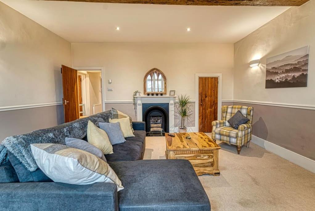 a living room with a blue couch and a fireplace at Guest Homes - Harrow Croft Dwelling in Worcester