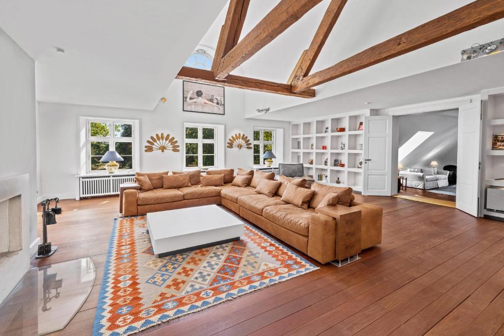 a living room with a couch and a table at GUT KLETKAMP "Penthouse im Schloss" - Premium-Ferienwohnung mit 5 Schlafzimmern auf 400qm I Kamin I 2 Wohnzimmer I Garten & Terrasse I Wald- und Seeblick I Profi-Küche I 15 Min zur Ostsee I Parkplätze I WLAN in Kletkamp