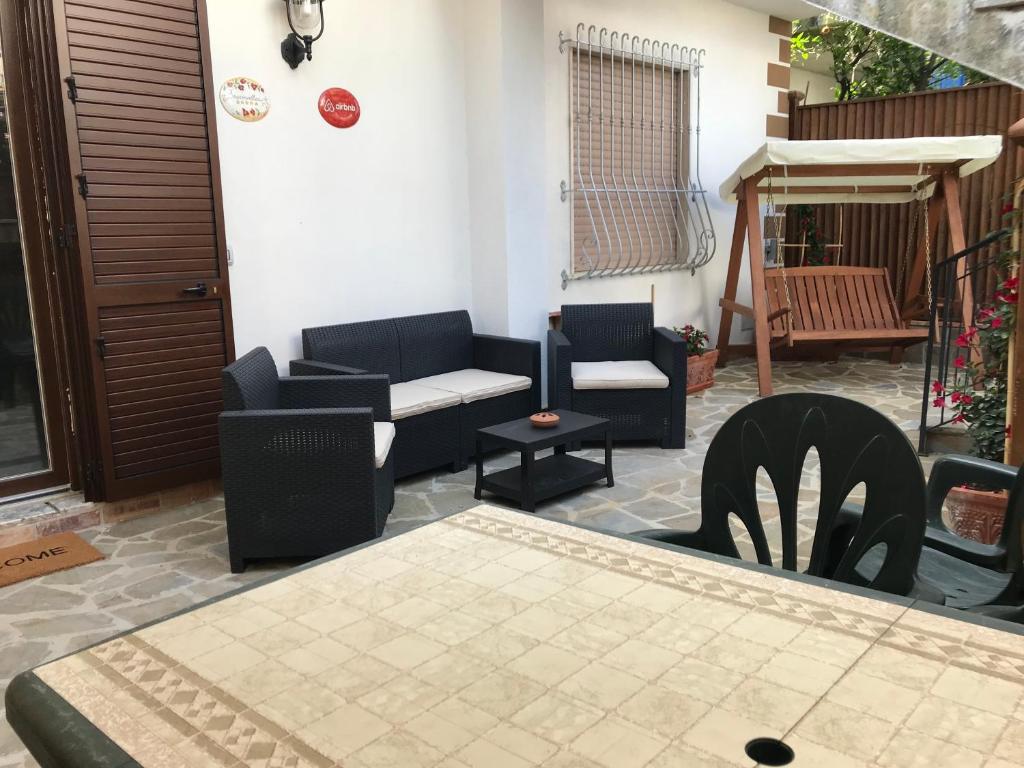 un patio con sedie, divano e tavolo di [VICINO AL MARE] Bougainvillea House a Marina di Casalvelino