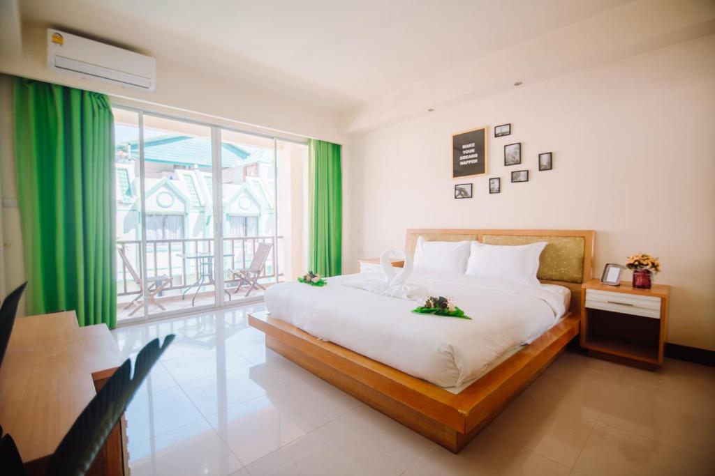 1 dormitorio con 1 cama grande y cortinas verdes en Patong Beach Side Hotel en Patong
