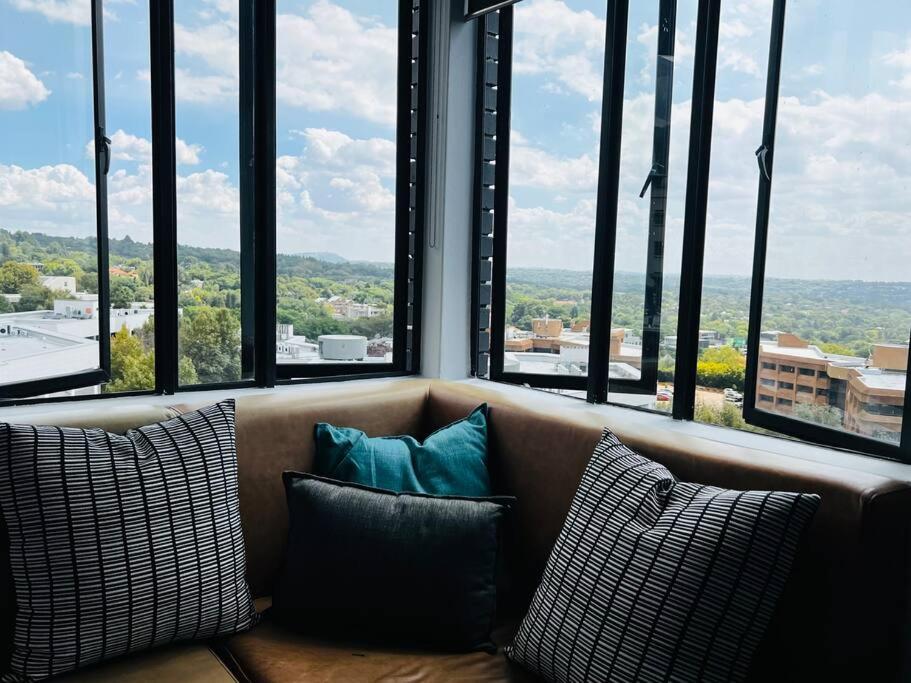 a couch with pillows in a room with windows at Apartment 4023-stunning views in Sandton in Johannesburg