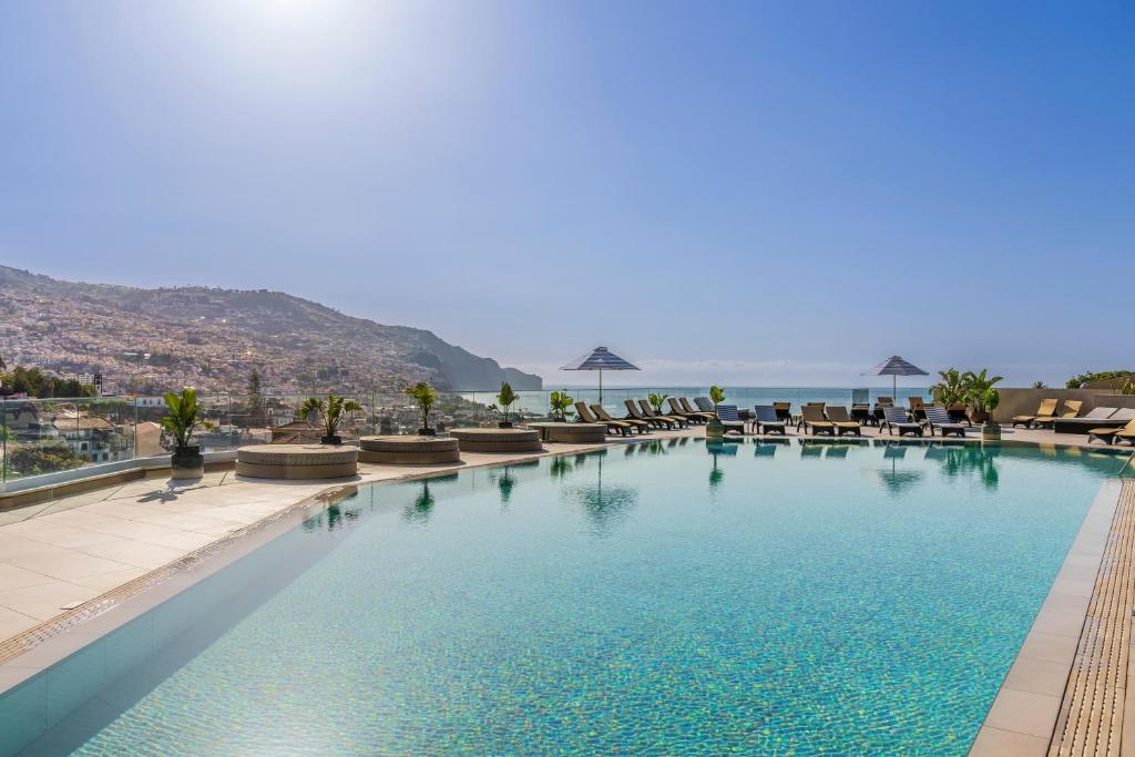 a swimming pool with chairs and the ocean in the background at The Views Baia - Adults Only in Funchal