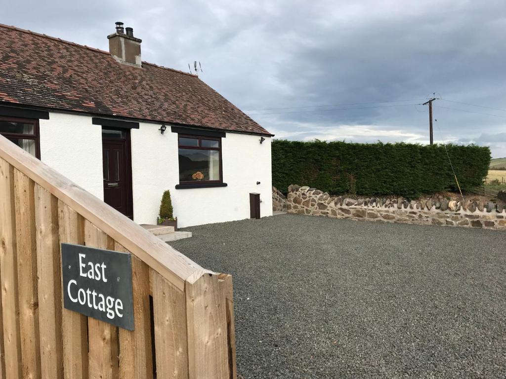 uma casa branca com um cartaz que diz "Casa de Campo Leste" em East Cottage at Parbroath Farm em Cupar