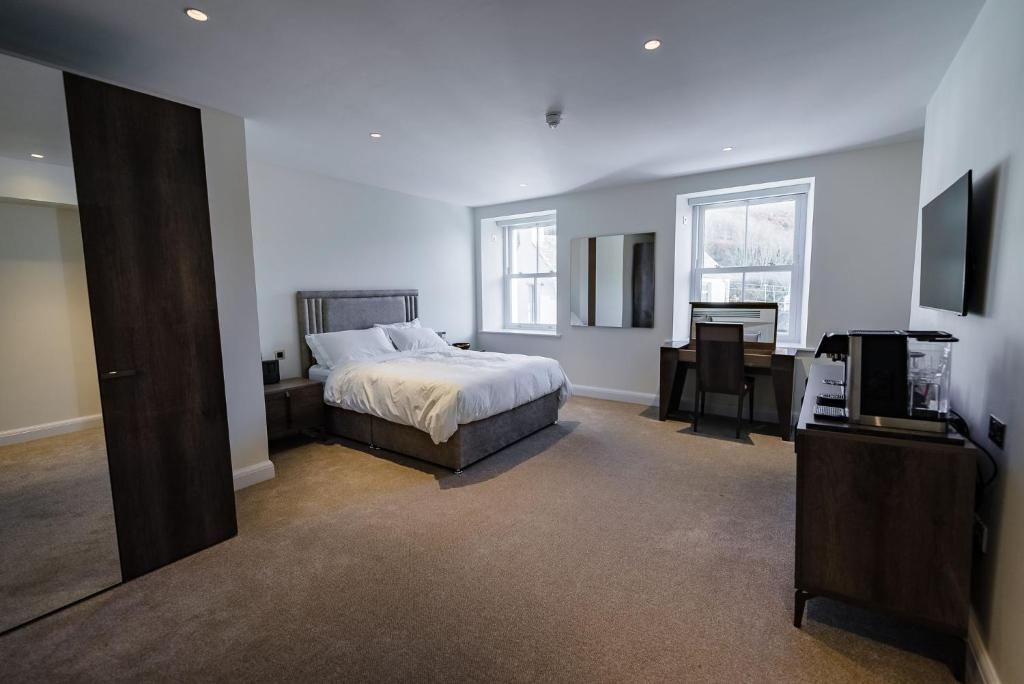a bedroom with a bed and a desk and a television at Shore Hotel Laxey in Laxey