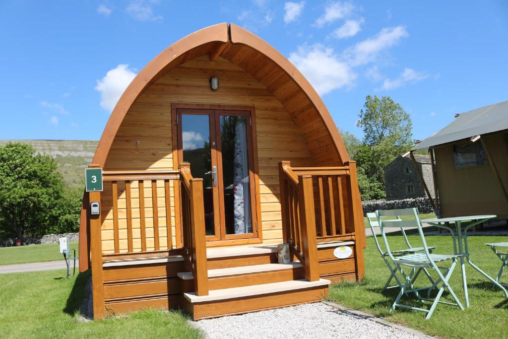 a small wooden cabin with stairs and a door at Littondale Country & Leisure Park in Skipton