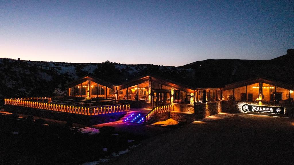 a building with lights in front of it at night at Hotel Xaluca Spa Aguelmame Sidi Ali in Aguelman