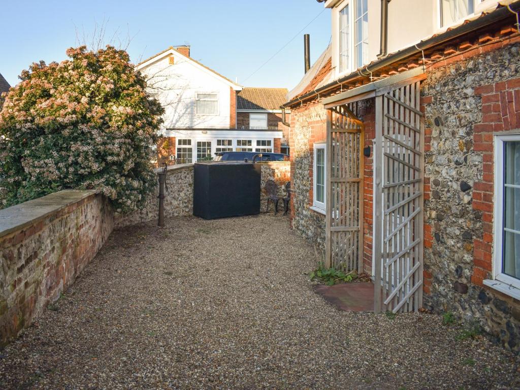 an alleyway leading to a brick house with a gate at Pump Cottage in Brancaster