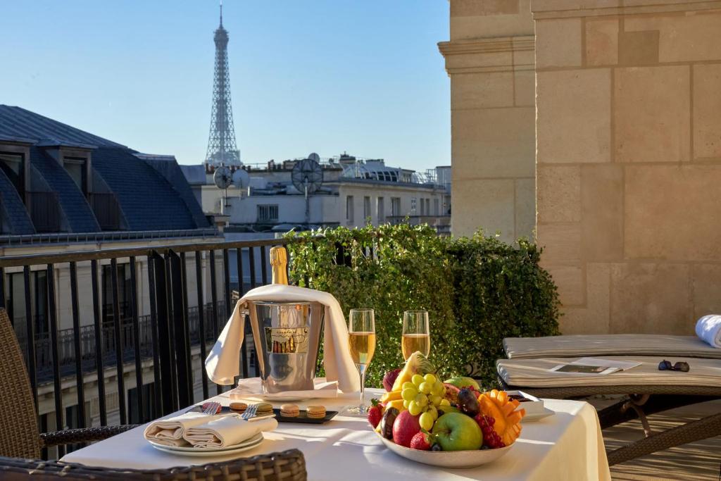 a table with a bowl of fruit and glasses of wine at Hôtel Raphael in Paris