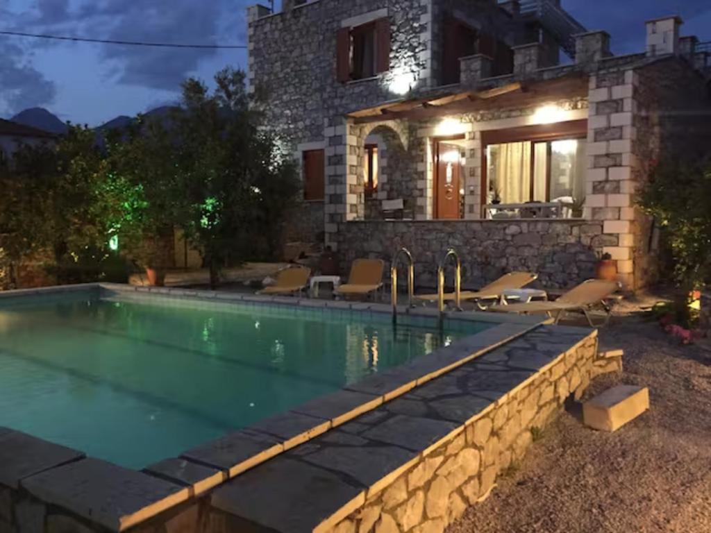 a villa with a swimming pool in front of a house at Sunshine Villa in Stoupa