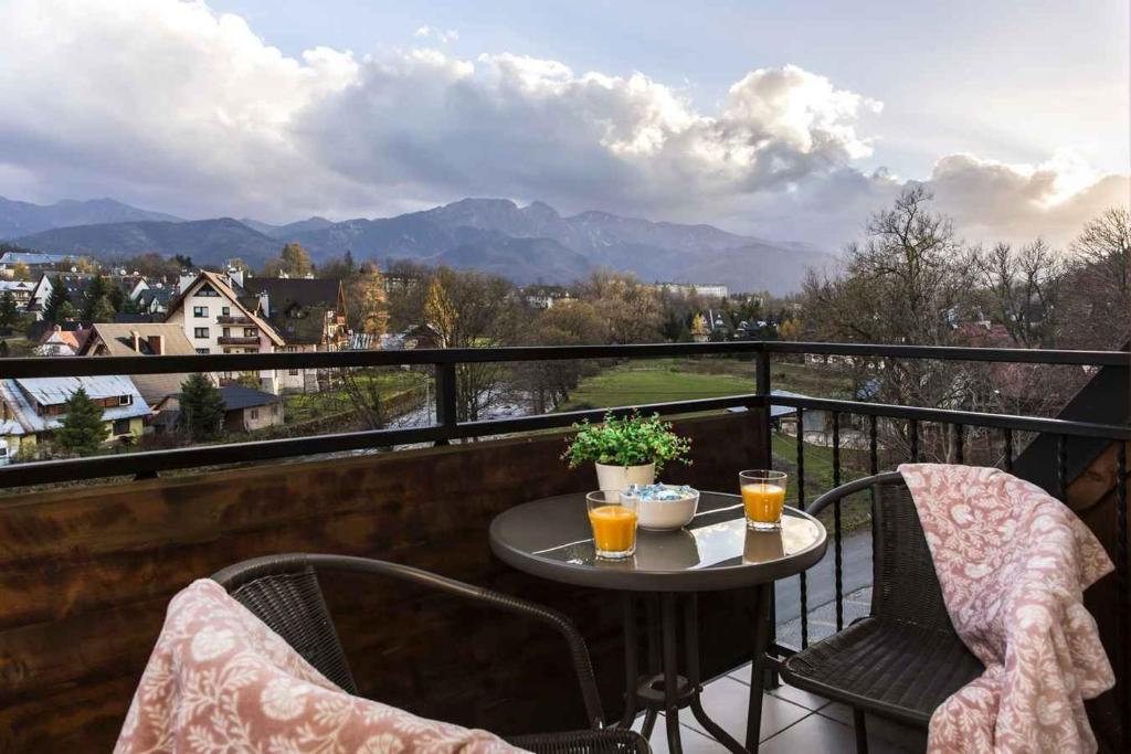 een tafel en stoelen op een balkon met uitzicht bij Apartament De Lux Cicha Woda in Zakopane