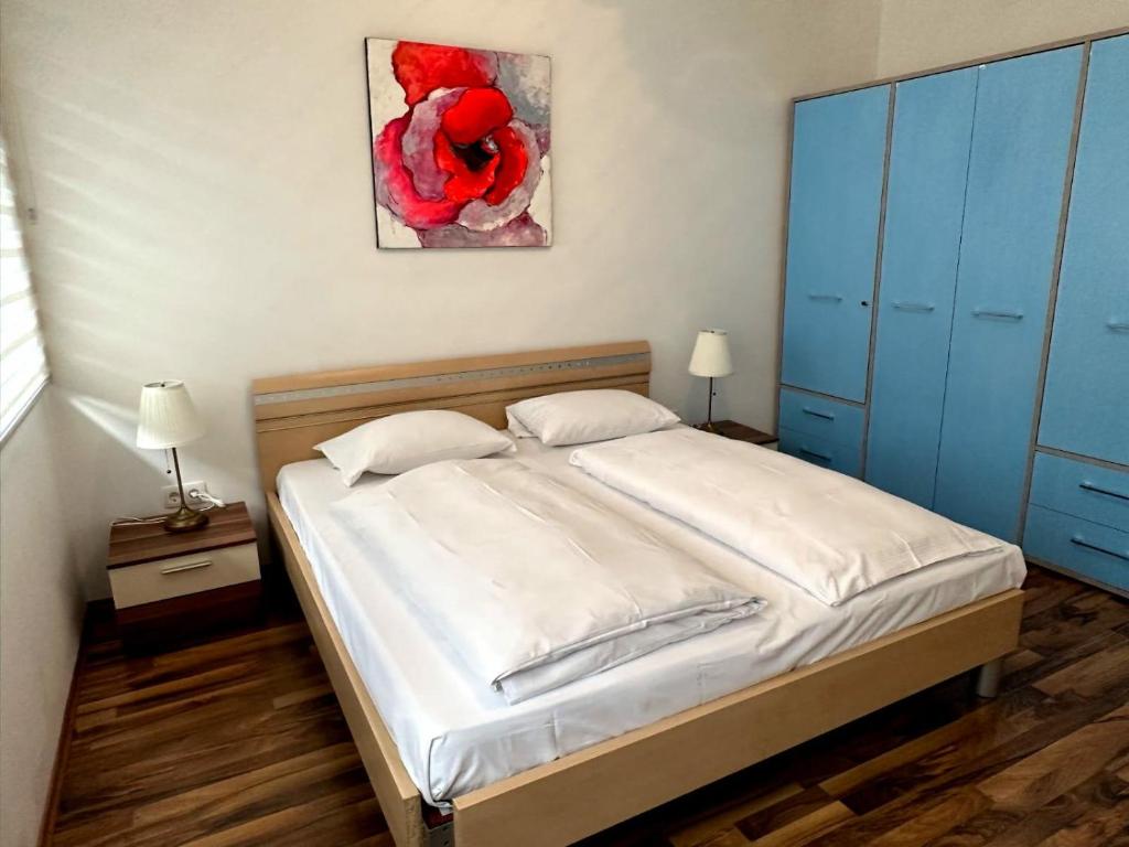 um quarto com uma cama com lençóis brancos e armários azuis em Willy Studio Apartment Frankfurt em Frankfurt