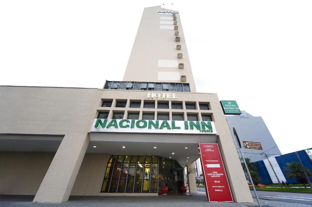 un grand bâtiment blanc avec un panneau national. dans l'établissement Hotel Nacional Inn Curitiba Torres, à Curitiba