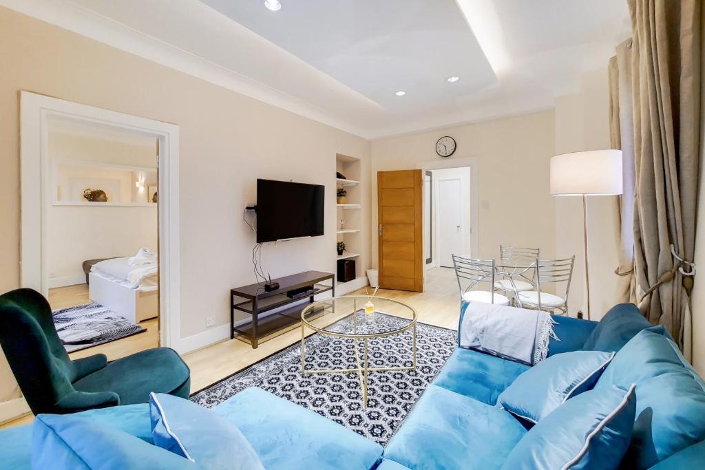 een woonkamer met een blauwe bank en een televisie bij The Quebec Residence in Londen