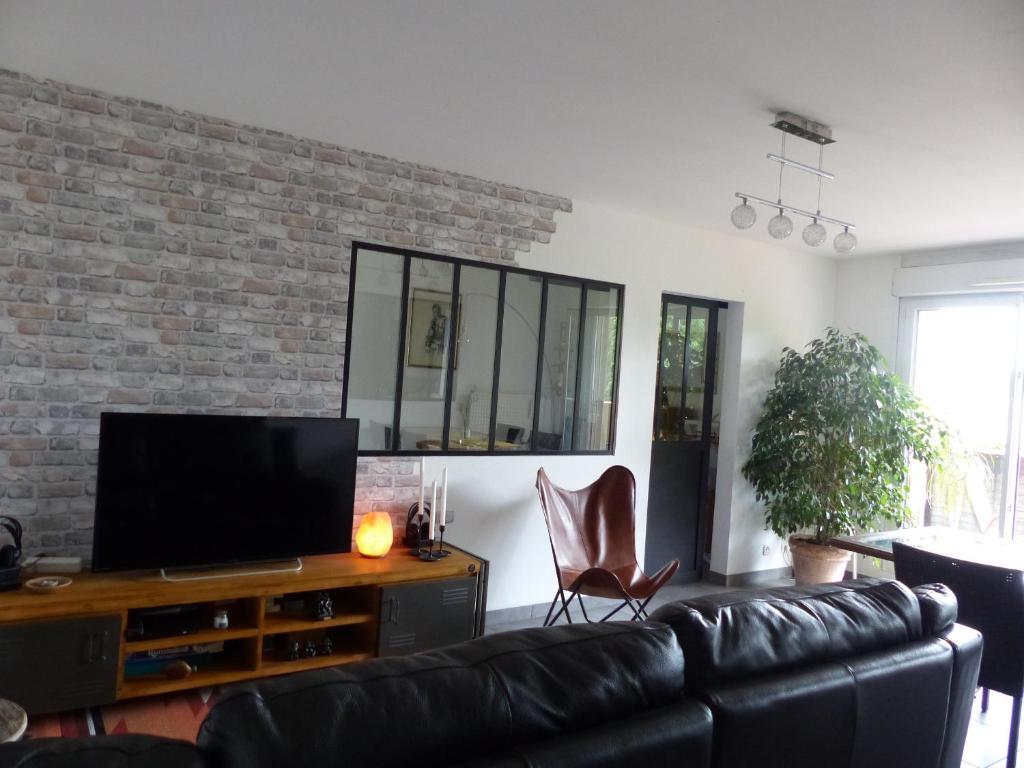 a living room with a couch and a flat screen tv at Appartement cosy 4 personnes in Mâcon