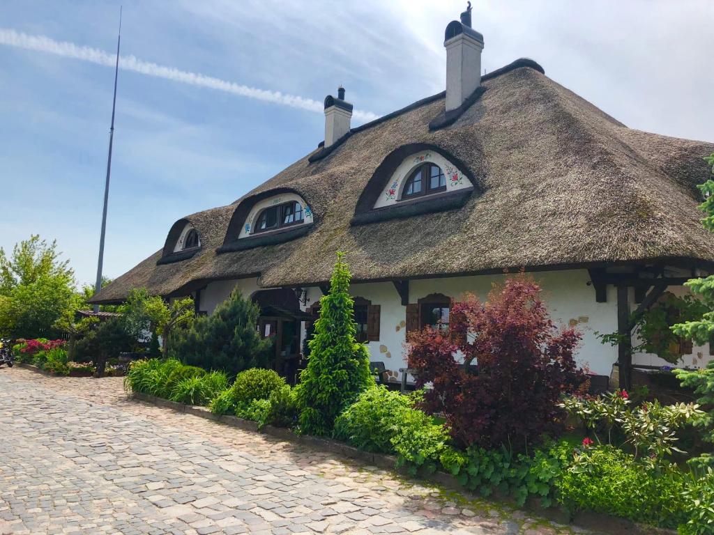 a thatched house with a cobblestone street in front at Gościniec Oycowizna in Lesznowola