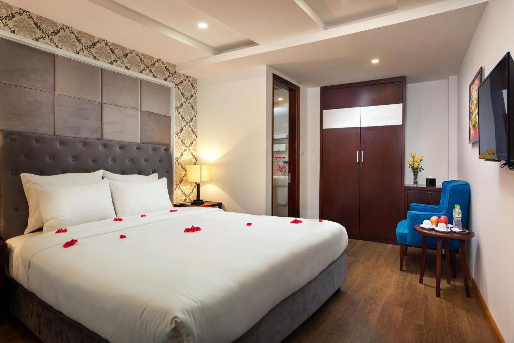 a bedroom with a large bed and a blue chair at Skyline Hanoi Hotel in Hanoi