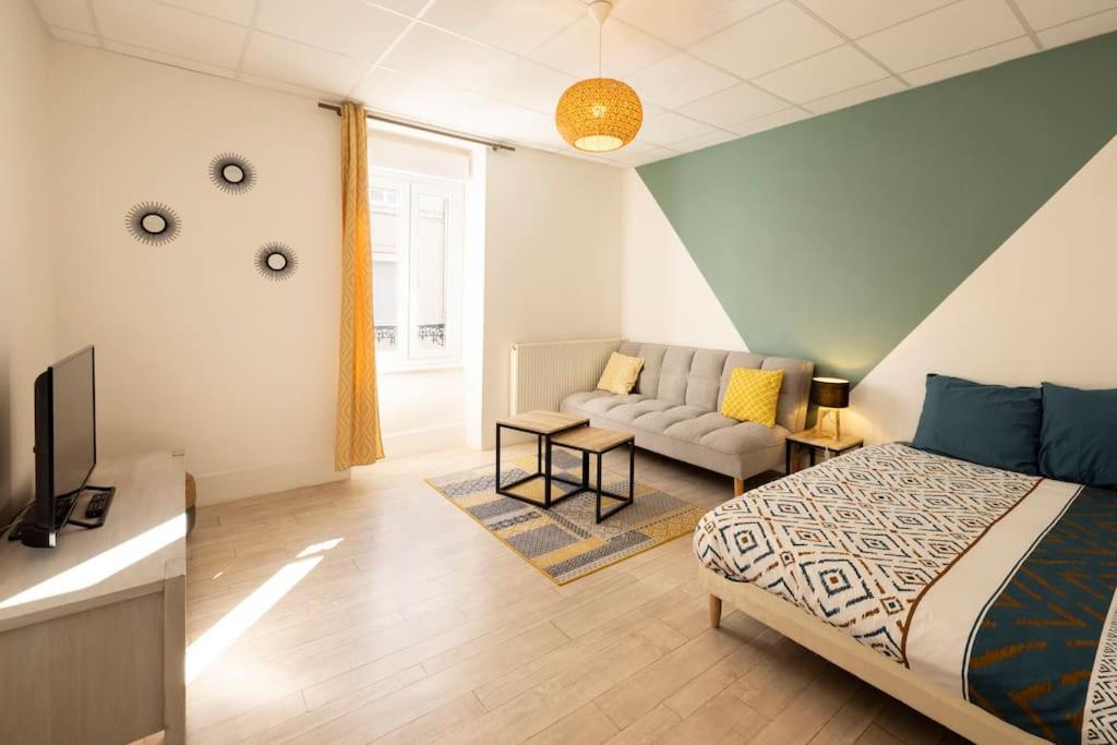 um quarto com uma cama, uma televisão e um sofá em Le Central A - Tout équipé - Centre-Ville Gare em Montluçon