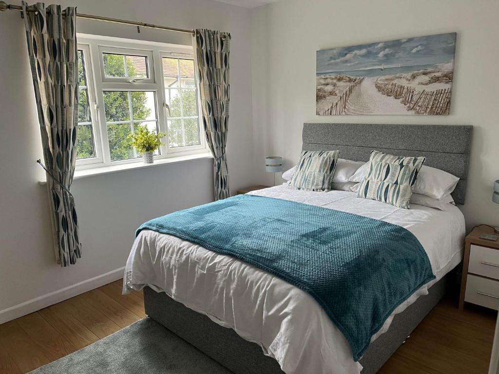 a bedroom with a bed and two windows at Estuary view in Exmouth