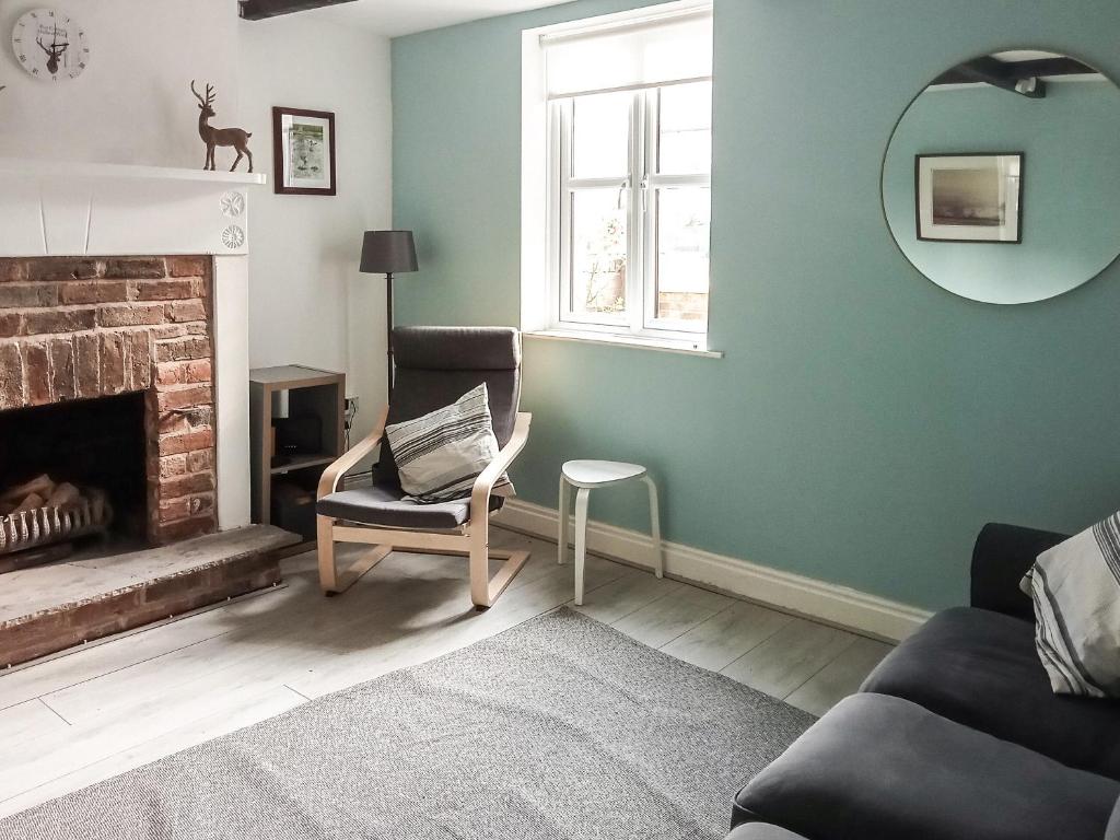 a living room with a chair and a fireplace at Post Cottage in Hulland