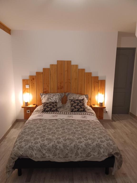 une chambre avec un grand lit avec une tête de lit en bois dans l'établissement la maison du bonheur, à Saint-Germain-Laval