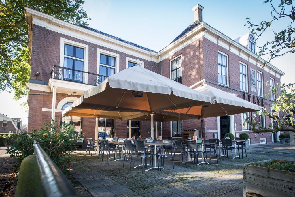 eine Terrasse mit Tischen, Stühlen und Sonnenschirmen vor einem Gebäude in der Unterkunft Boutique Hotel Brasa Beemster in Middenbeemster