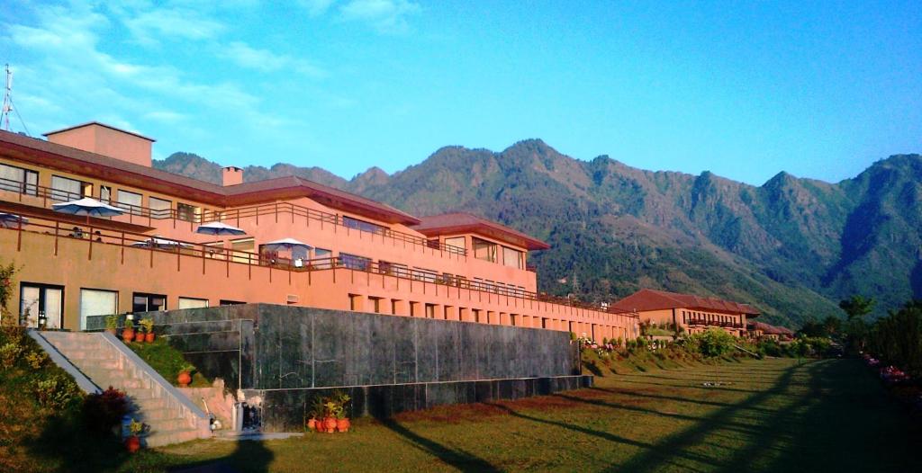 un grand bâtiment avec des montagnes en arrière-plan dans l'établissement Vivanta Dal View, à Srinagar
