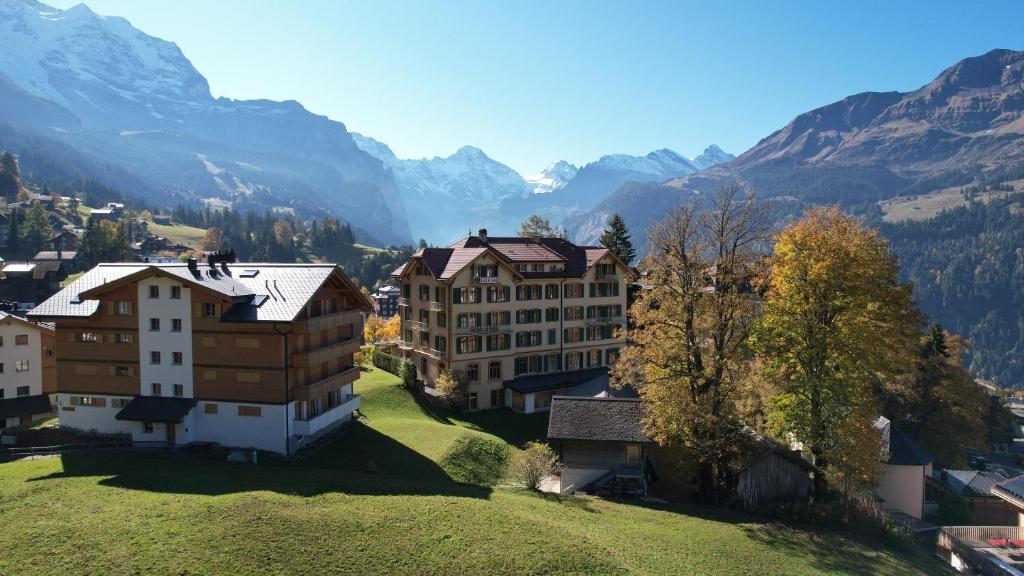 a village on a hill with mountains in the background at Historic Hotel Falken in Wengen