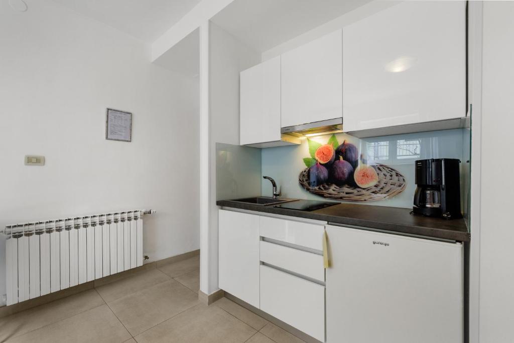 a kitchen with white cabinets and a bowl of fruit on the counter at Guesthouse Casa Nova in Poreč
