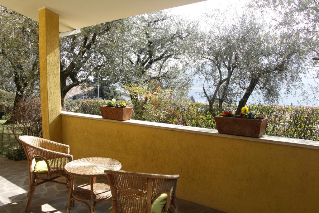 un patio avec des chaises et des tables ainsi qu'une fenêtre avec des arbres dans l'établissement Sarnico giardino sul lago, à Sarnico