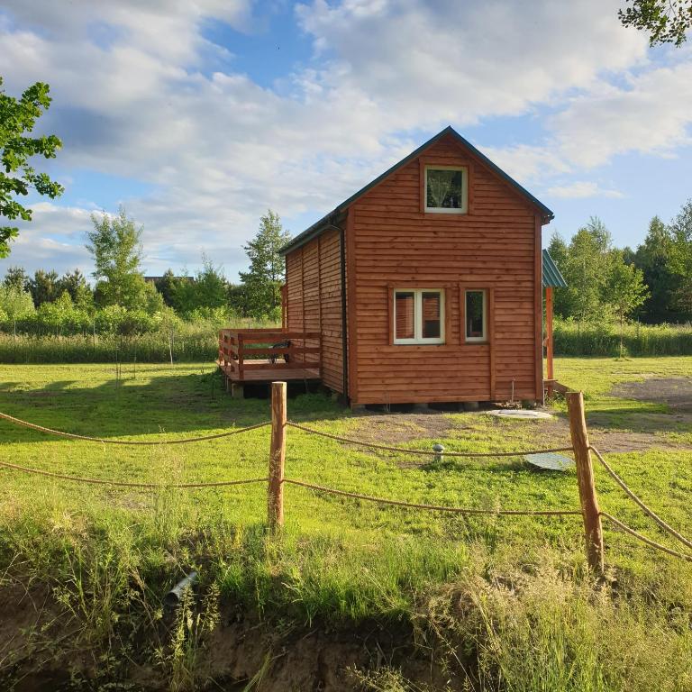 a small house in a field with a fence at JEZIORAKI Uroczy domek i sauna 400m od jeziora Nowa Jedlanka in Jedlanka Nowa