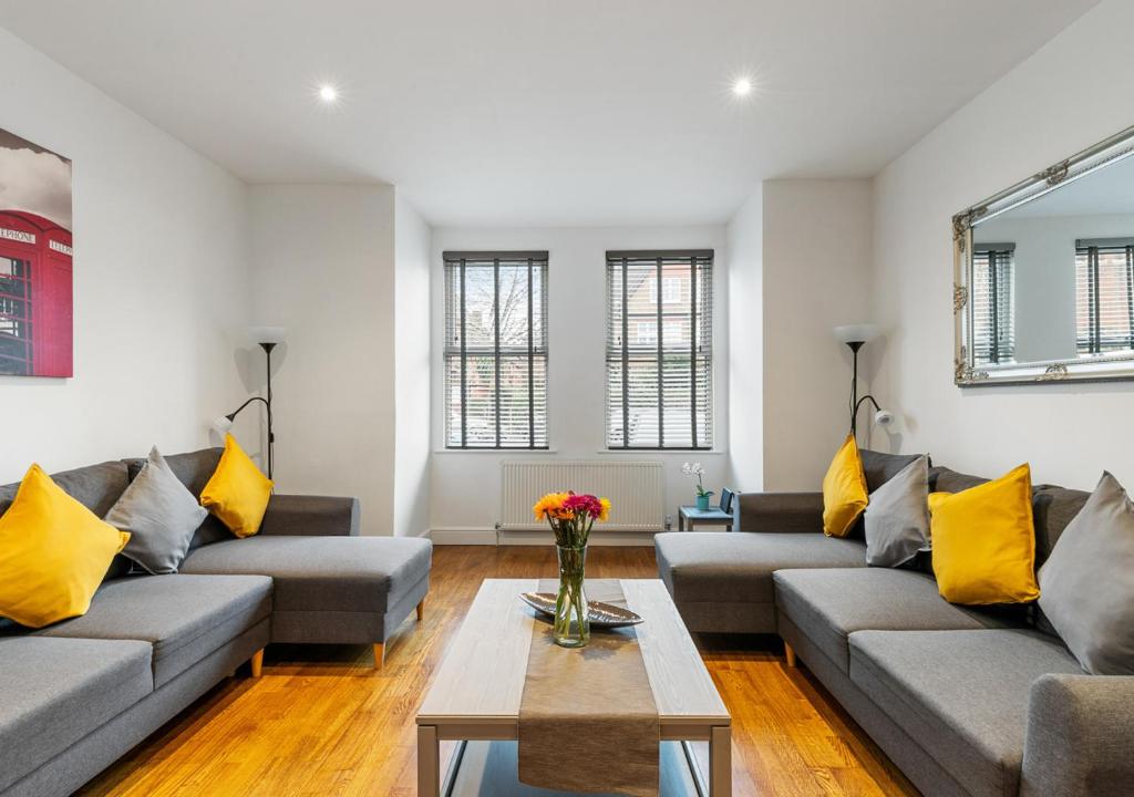 una sala de estar con sofás grises y almohadas amarillas en Two Bed Flat in Bush Hill Park, en Enfield