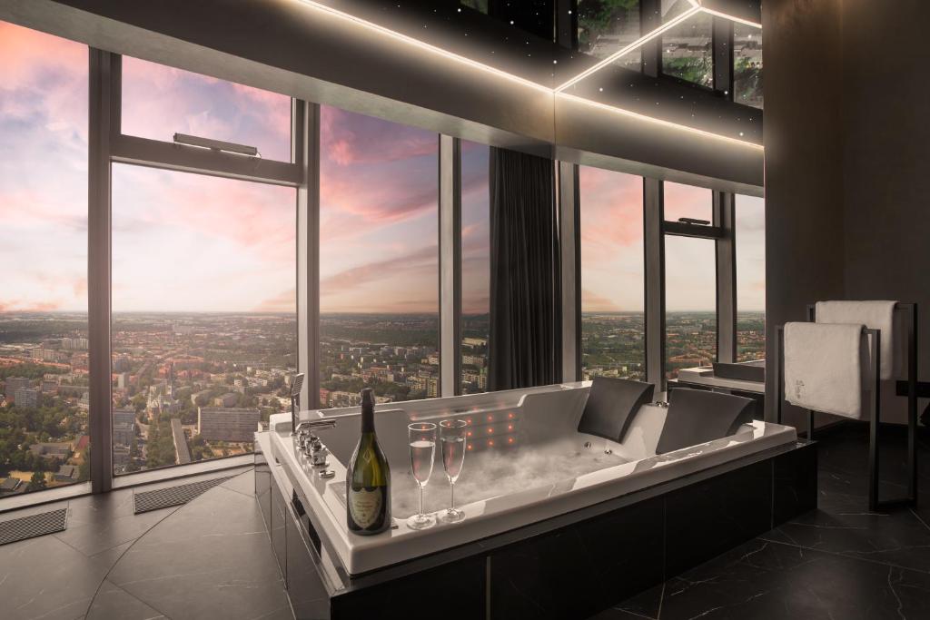 a bathroom with a soaking tub with a bottle of wine at In The Sky - Apartamenty w Sky Tower in Wrocław
