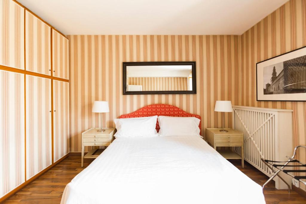 sypialnia z dużym białym łóżkiem z paskami w obiekcie Montenapoleone - Sant Andrea Charme PentHouse w Mediolanie