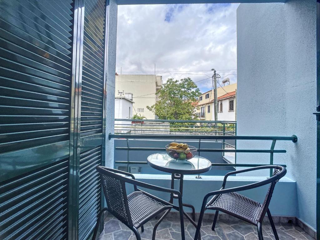 un tavolo e due sedie su un balcone con finestra di Milagres Apartment by Atlantic Holiday a Machico