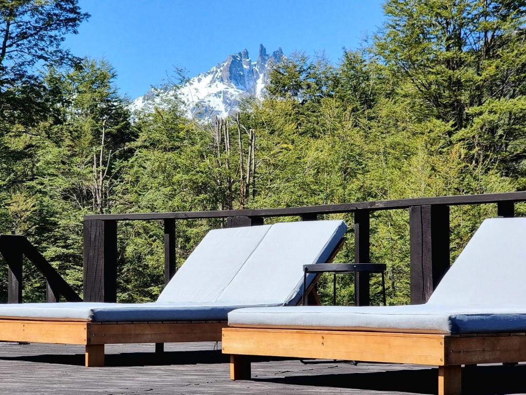 2 camas en una terraza con una montaña en el fondo en Peuma Lodge Patagonia, en Futaleufú
