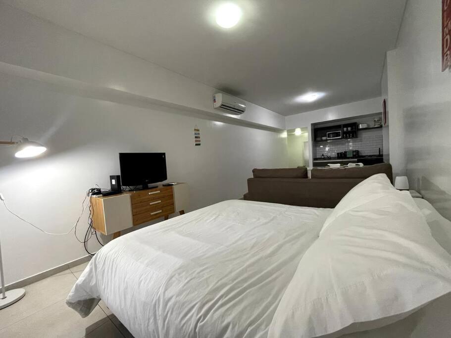 1 dormitorio con 1 cama blanca y TV en Deluxe apartment in great location en Buenos Aires